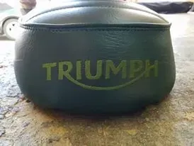 A triumph motorcycle seat is sitting on the ground.
