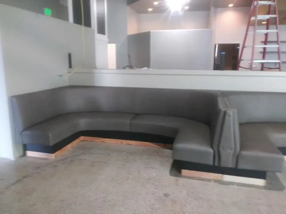 A booth in a restaurant with a ladder in the background