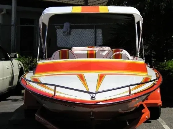 A red white and yellow boat is parked in a parking lot