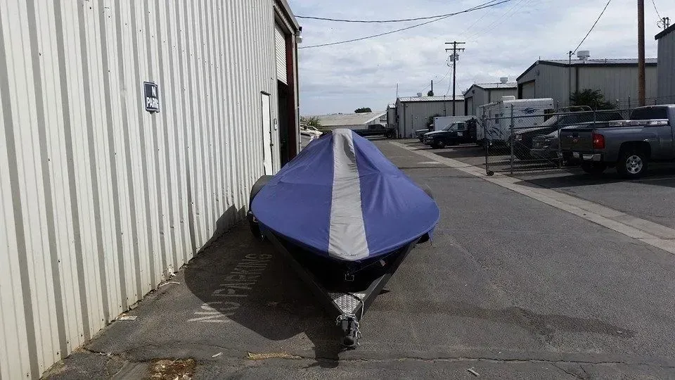 A boat with a cover on it is parked on the side of the road