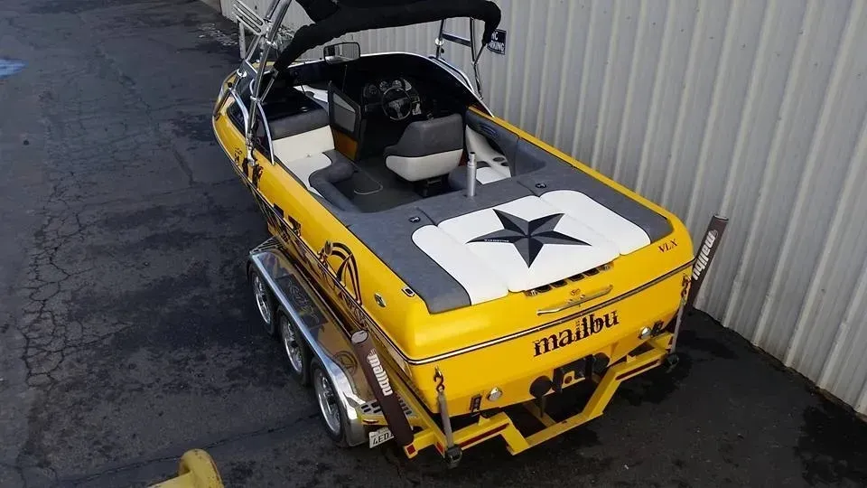 A yellow boat with a star on the back is parked in front of a building.