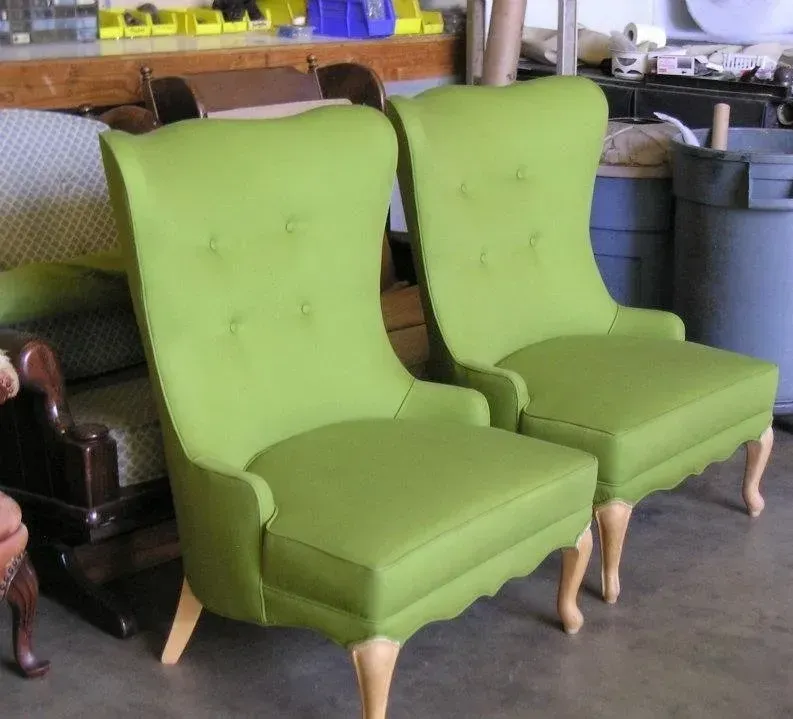 Two green chairs are sitting next to each other in a room