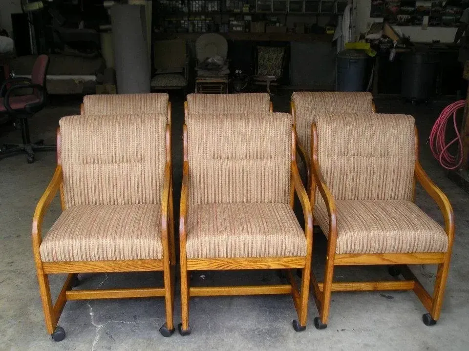 A row of chairs with wheels are lined up in a garage.