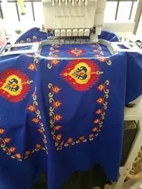 A blue table cloth is being embroidered on a machine.