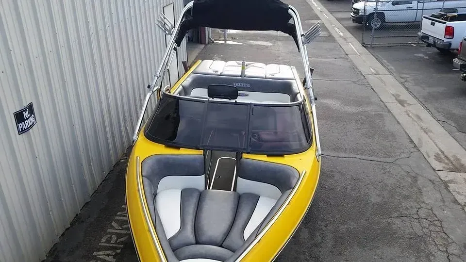 A yellow boat is parked in a parking lot next to a building.