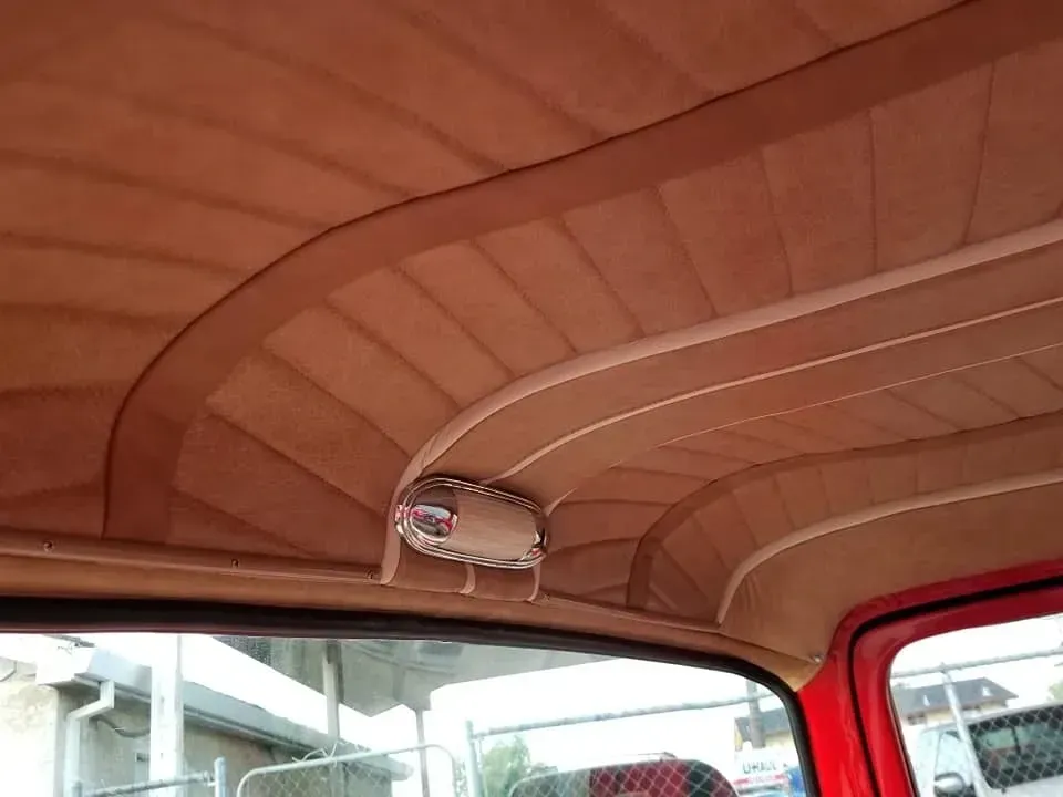 The ceiling of a red car with a light on it.