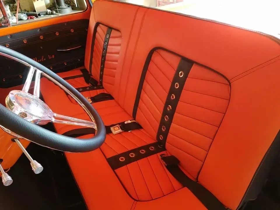 The inside of a car with orange seats and black seat belts