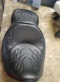 A black motorcycle seat with flames on it is sitting on a table.