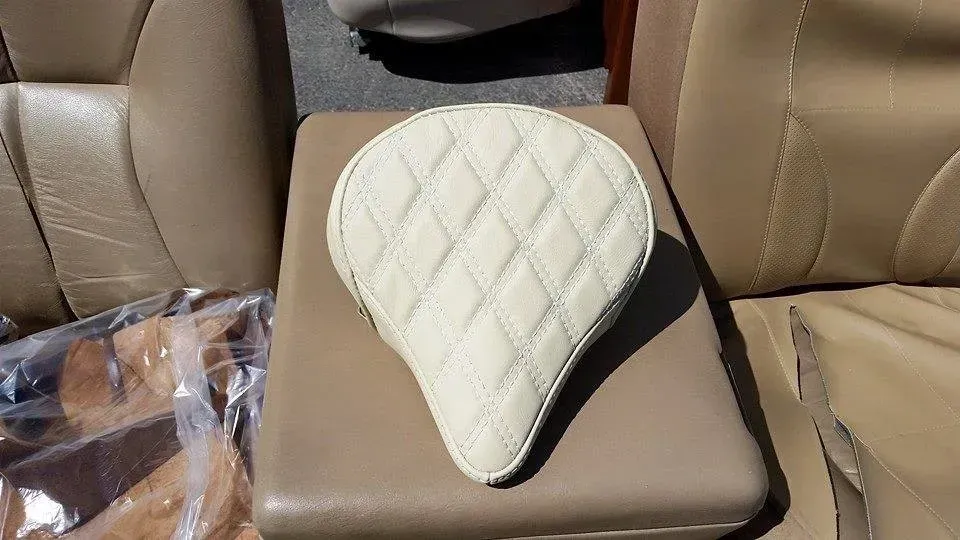 A white leather seat is sitting on a tan leather chair.