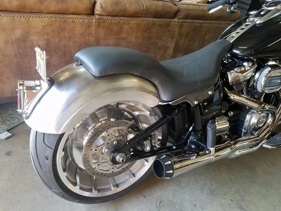 A black motorcycle is parked in front of a brown couch.