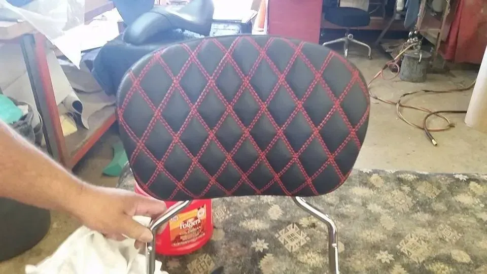 A person is holding a black and red chair in a room.