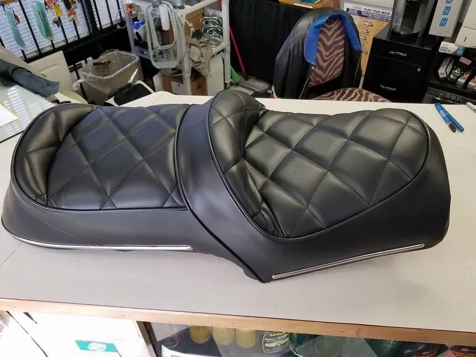 A black motorcycle seat is sitting on a table.