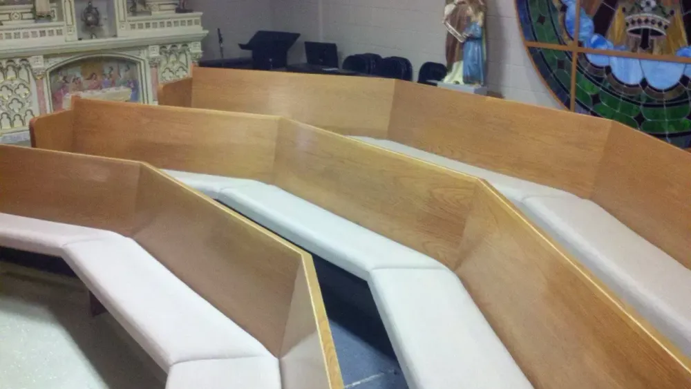 A row of wooden benches with white cushions in a room