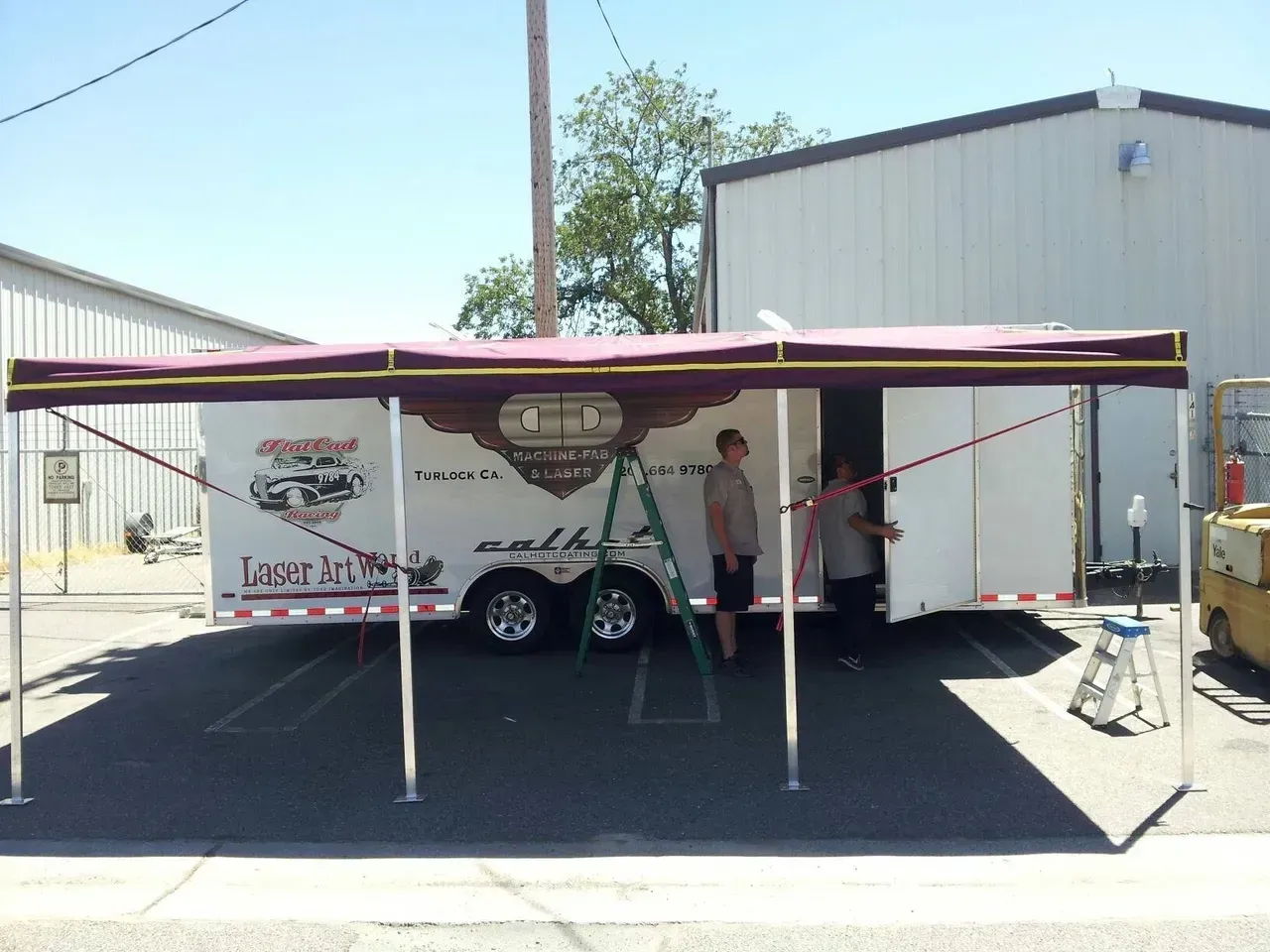 A white trailer with a purple awning on top of it