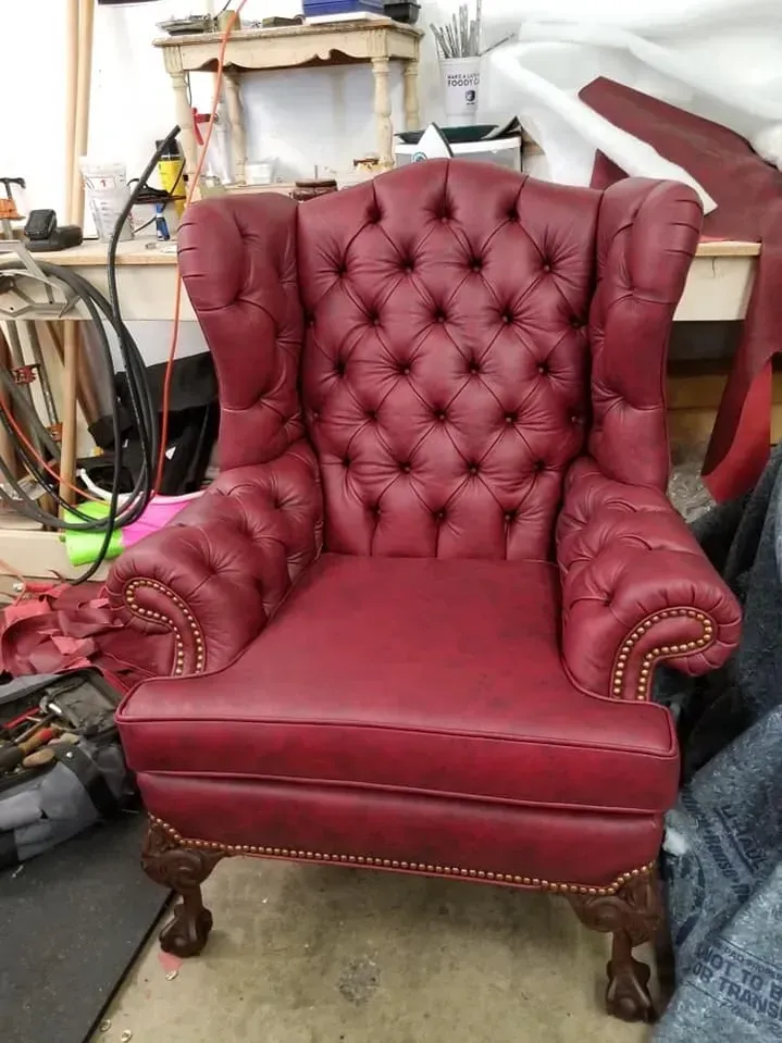 A red leather chair is sitting on the floor in a room.