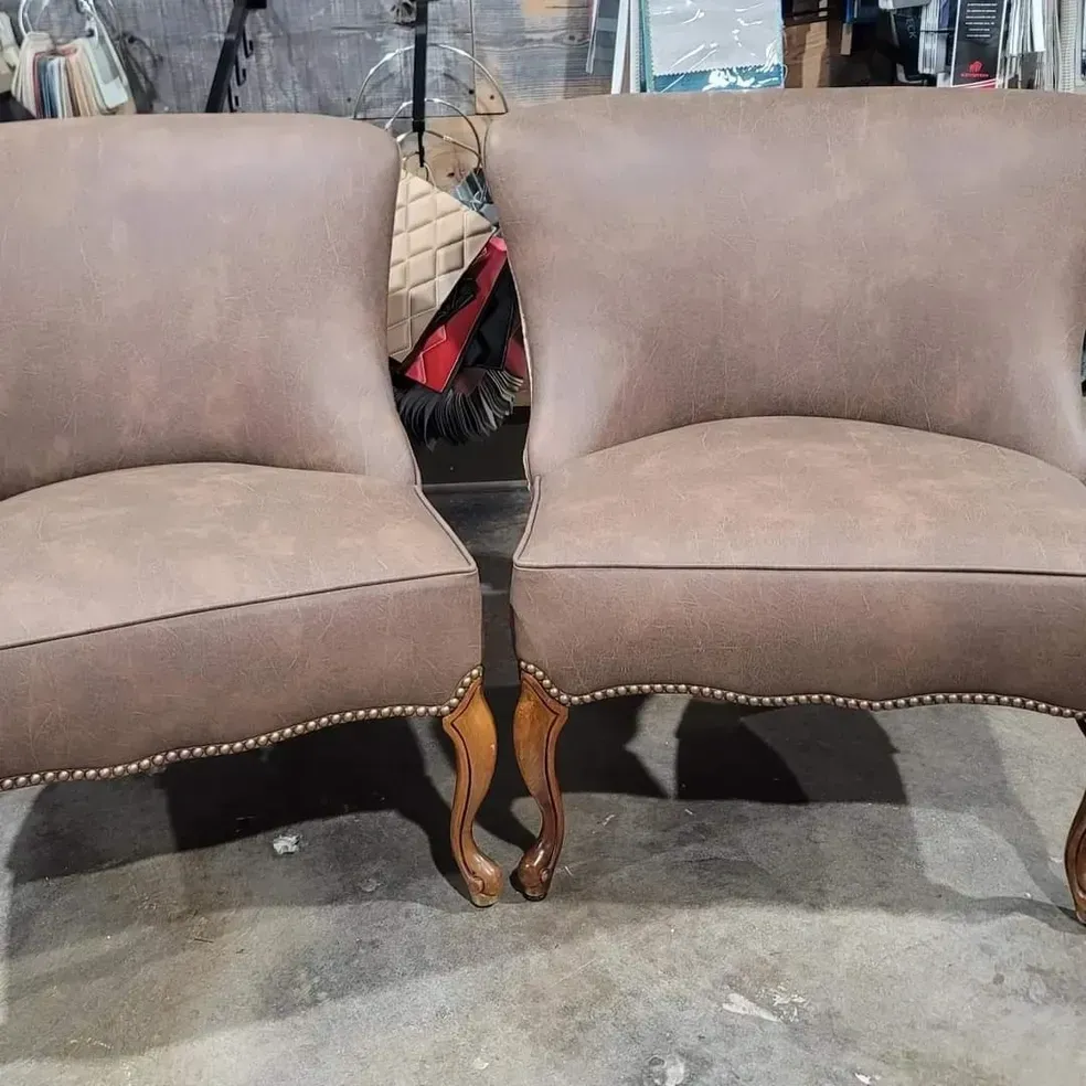 Two brown leather chairs are sitting next to each other on a concrete floor.
