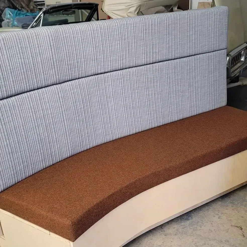 A curved couch with a brown cushion is sitting on the floor.