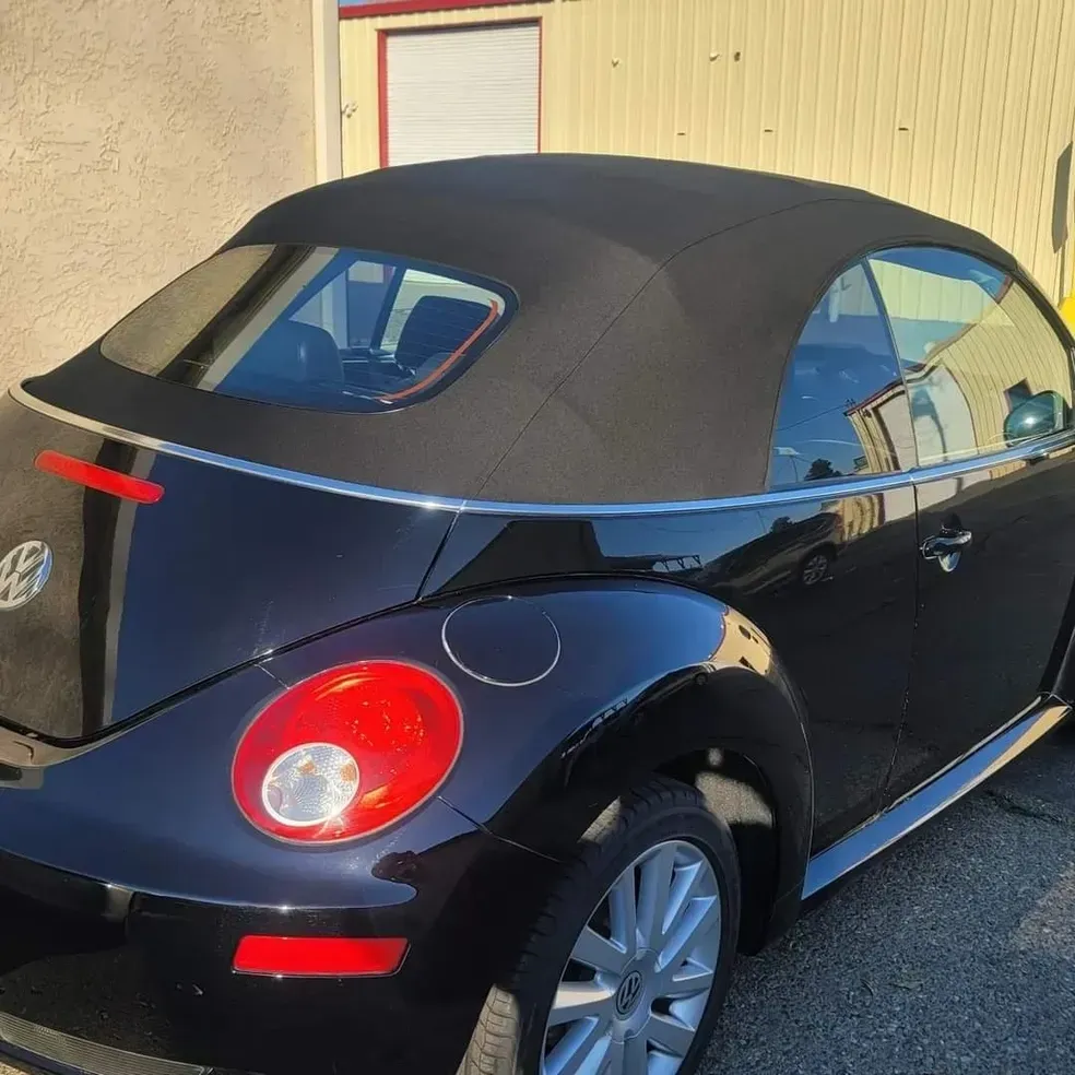 A black beetle with a black top is parked in front of a building