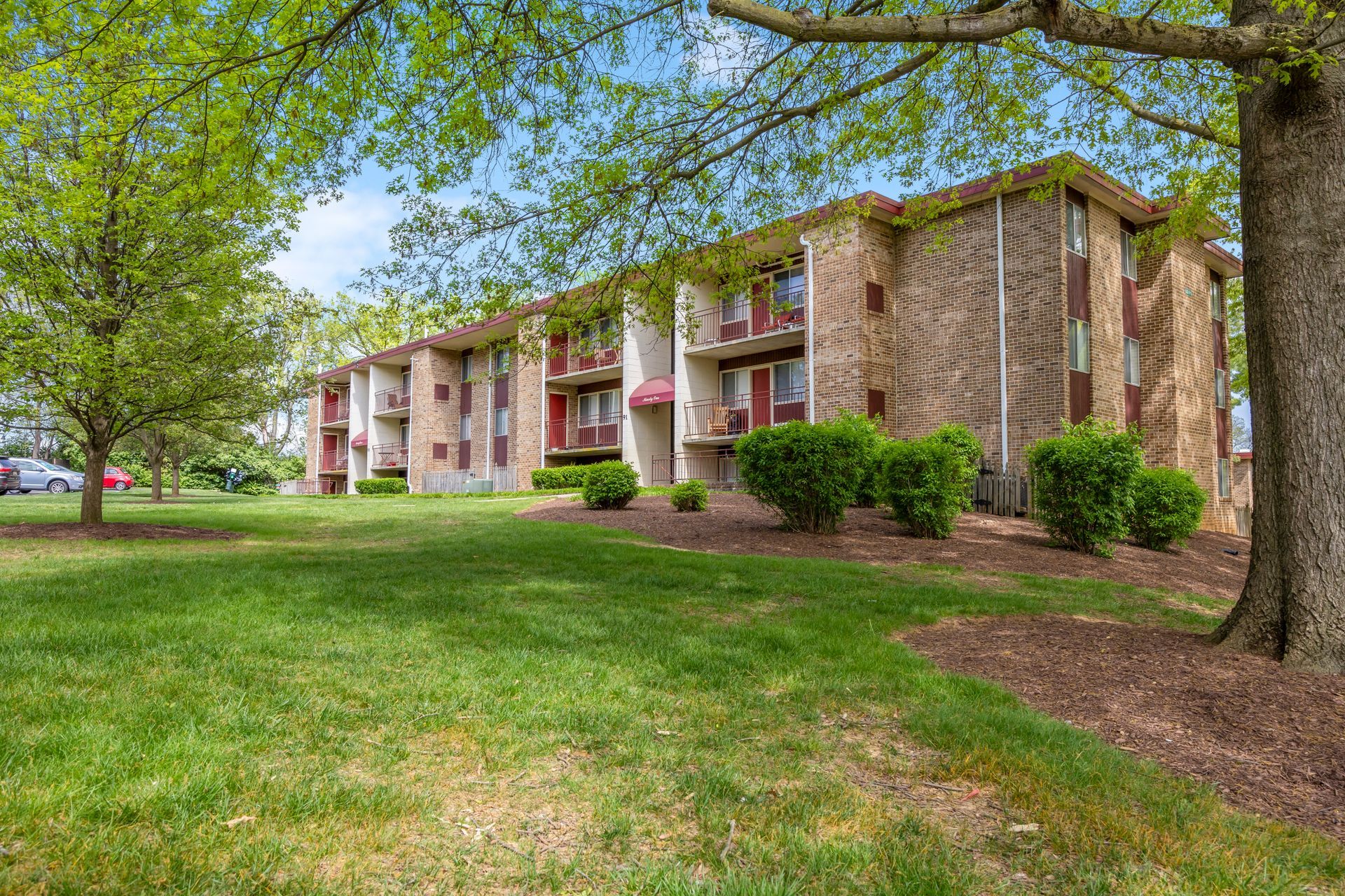 A large apartment building with a lush green lawn in front of it.