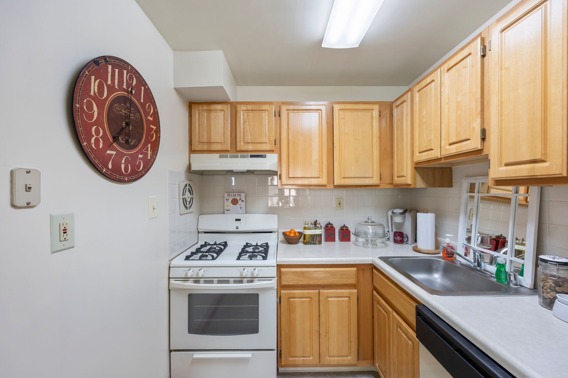 A kitchen with wooden cabinets and a clock on the wall