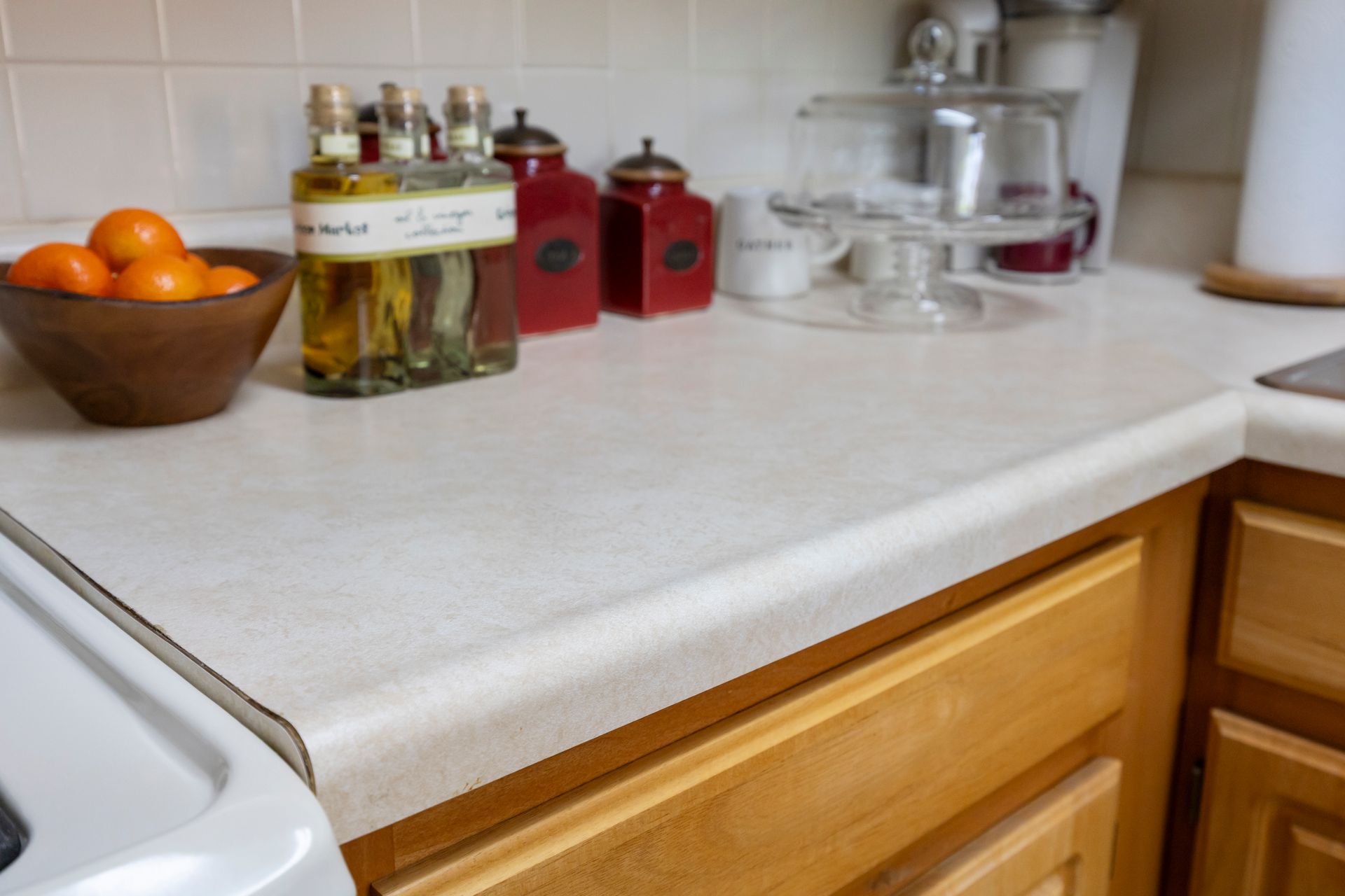 A kitchen counter with a bowl of oranges and bottles of oil