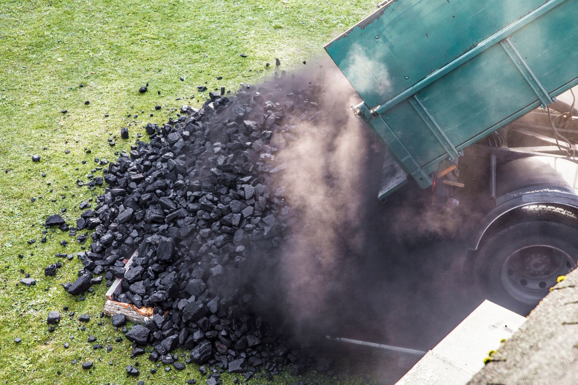 A dump truck is dumping coal into the ground.