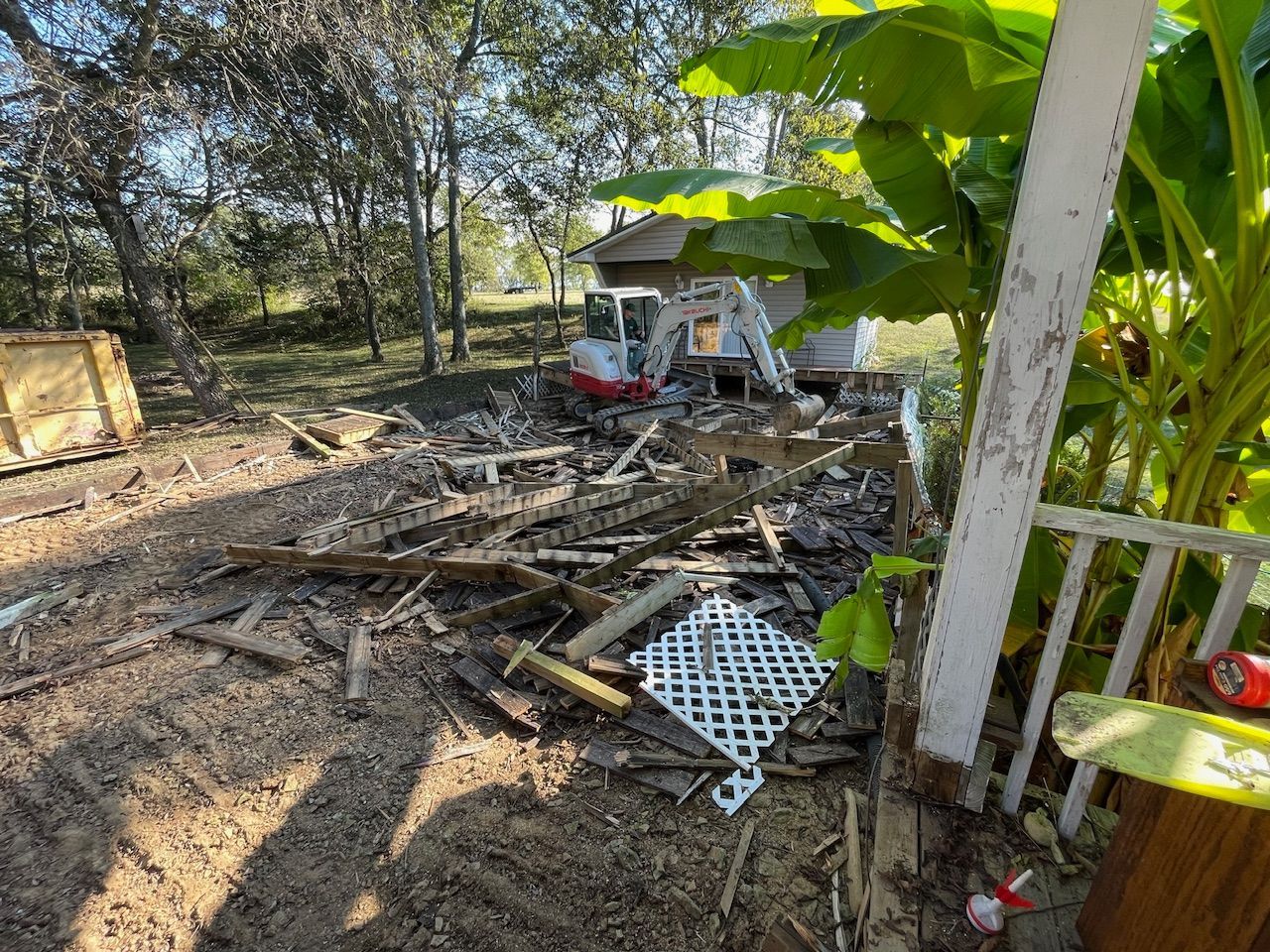 A house is being demolished with a bulldozer in the background.