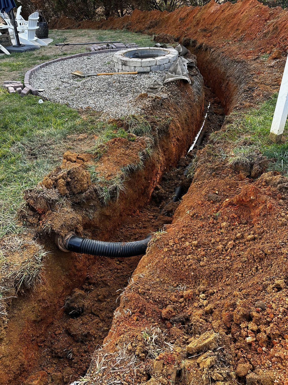 A large hole in the ground with a fire pit in the background.