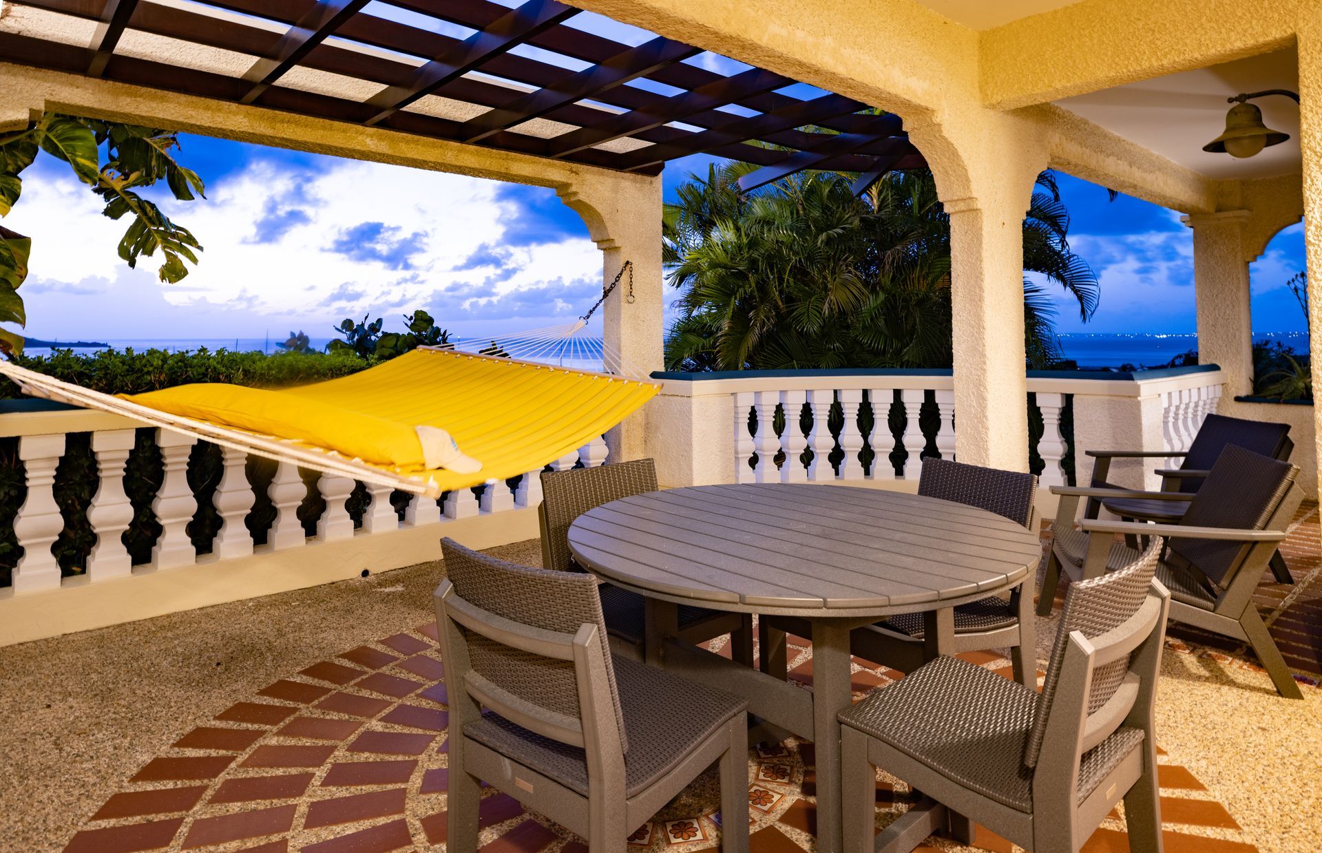 Covered patio with table and chairs, hammock, and view of the ocean.