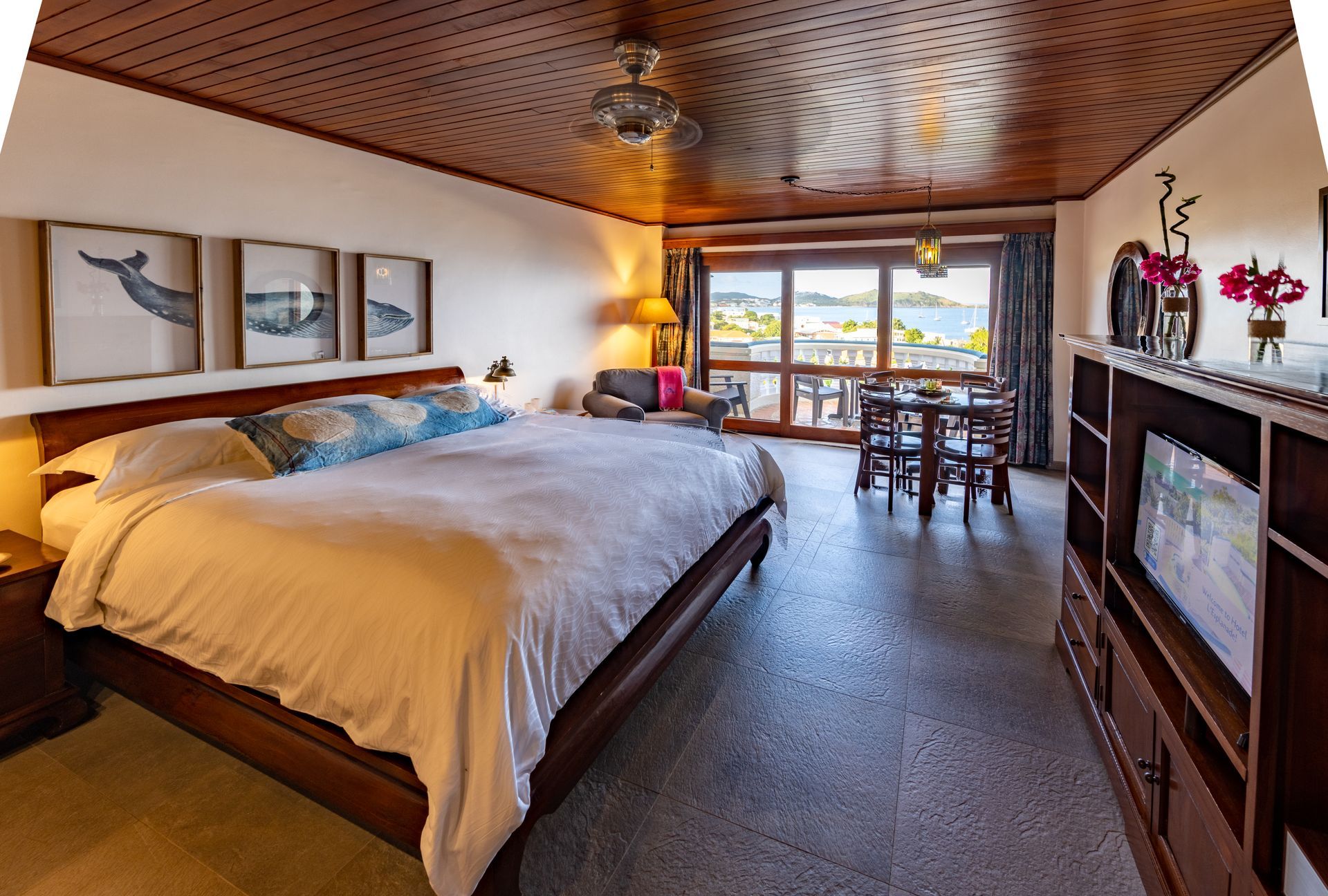 Bedroom with a large bed, wooden furniture, and a balcony view of water.