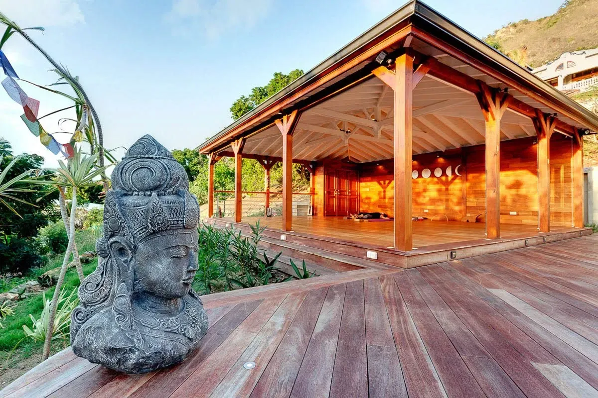 A wooden gazebo overlooking a deck with a stone Buddha statue in front.