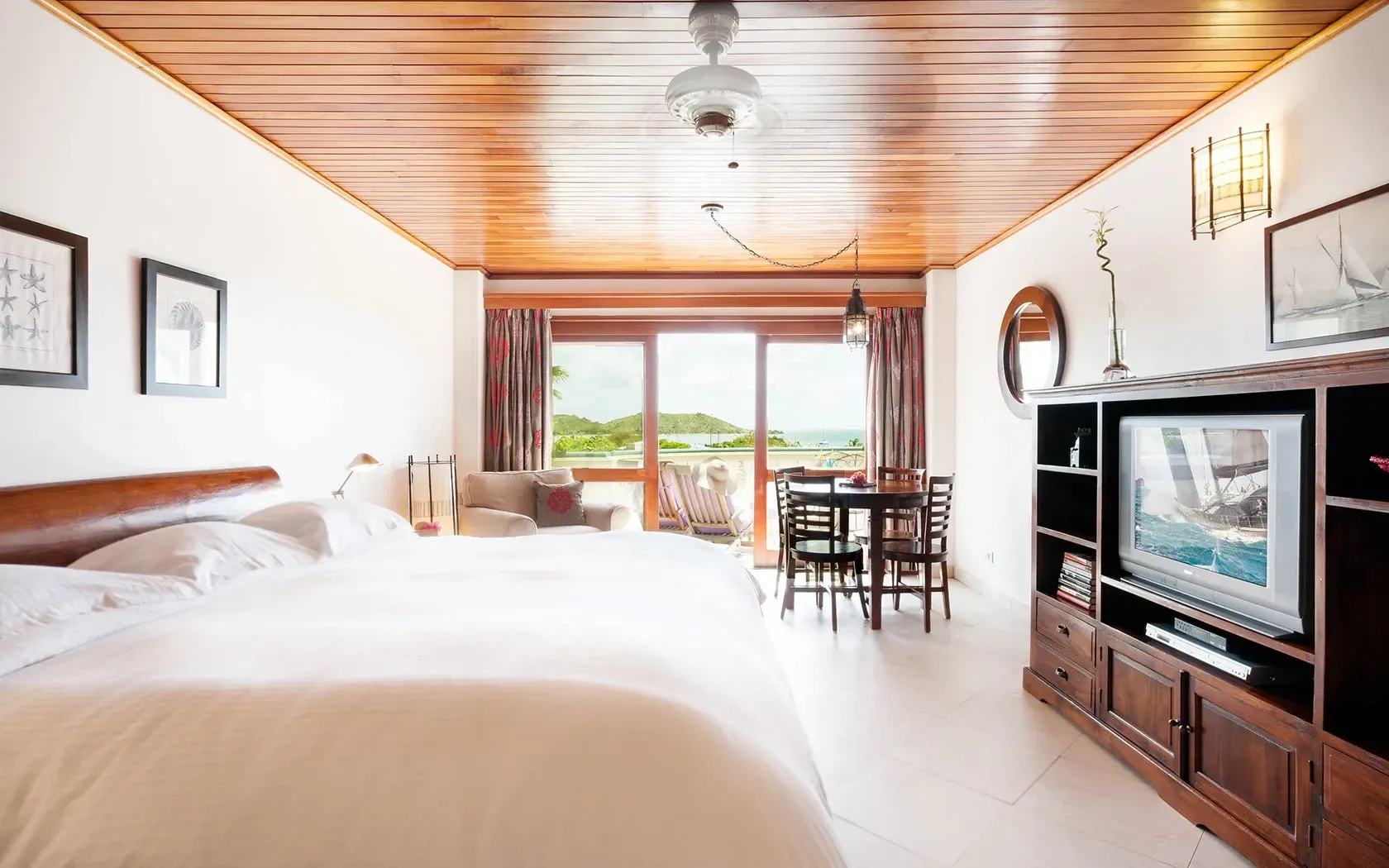 Bedroom studio with a wooden ceiling, white walls, and a balcony overlooking the ocean.