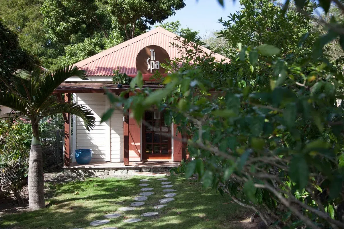 Spa building with red roof and arched spa sign, pathway through greenery.