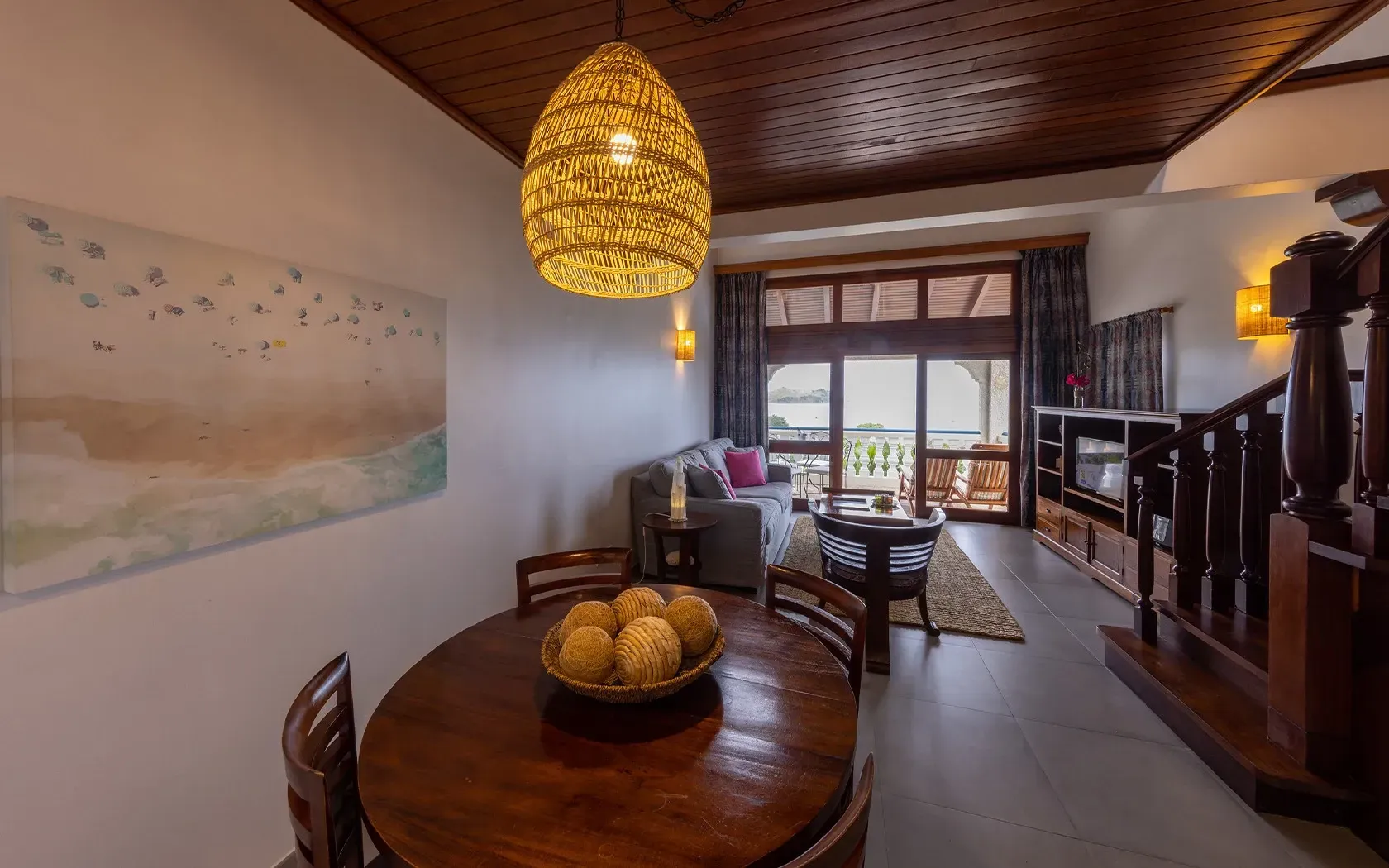 Dining area with wooden table, chandelier, and open doorway to balcony.