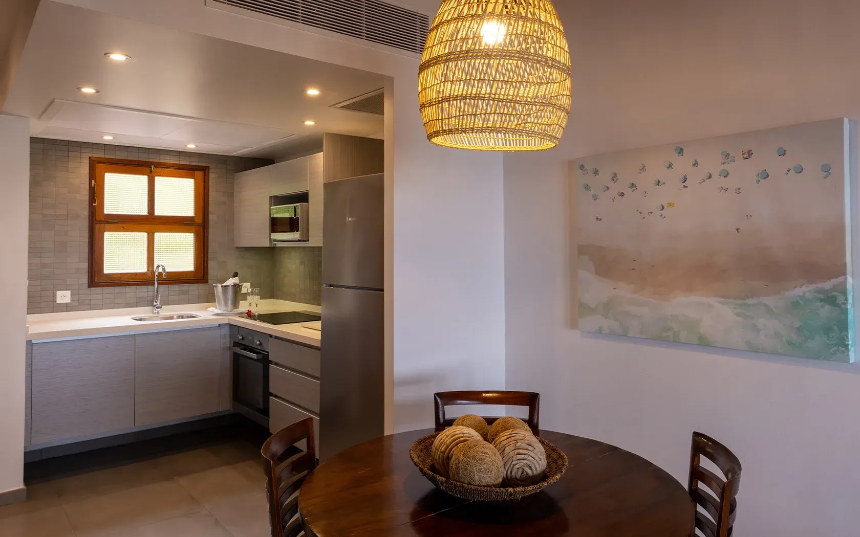 Kitchen and dining area with gray cabinets, wood table, and woven light fixture.