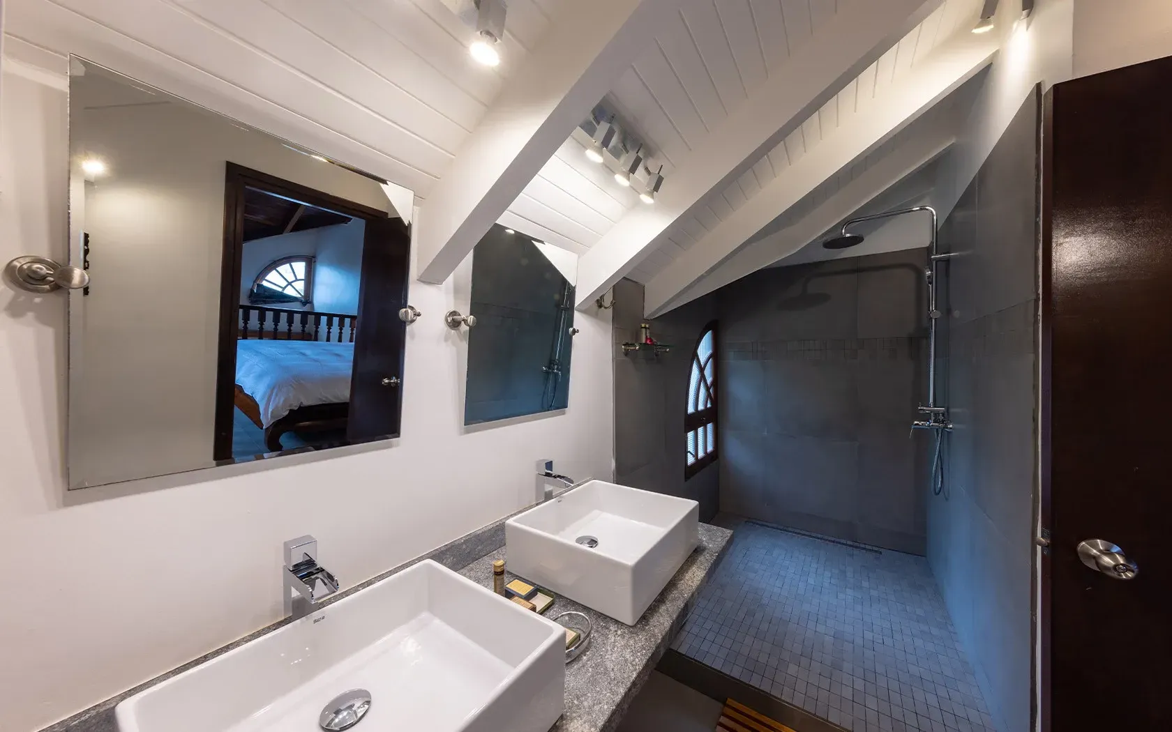 Bathroom with white sinks, mirrors, and a gray shower.