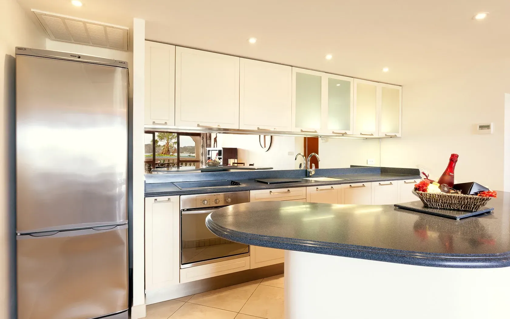 Modern kitchen with stainless steel appliances, white cabinets, and a dark countertop island.