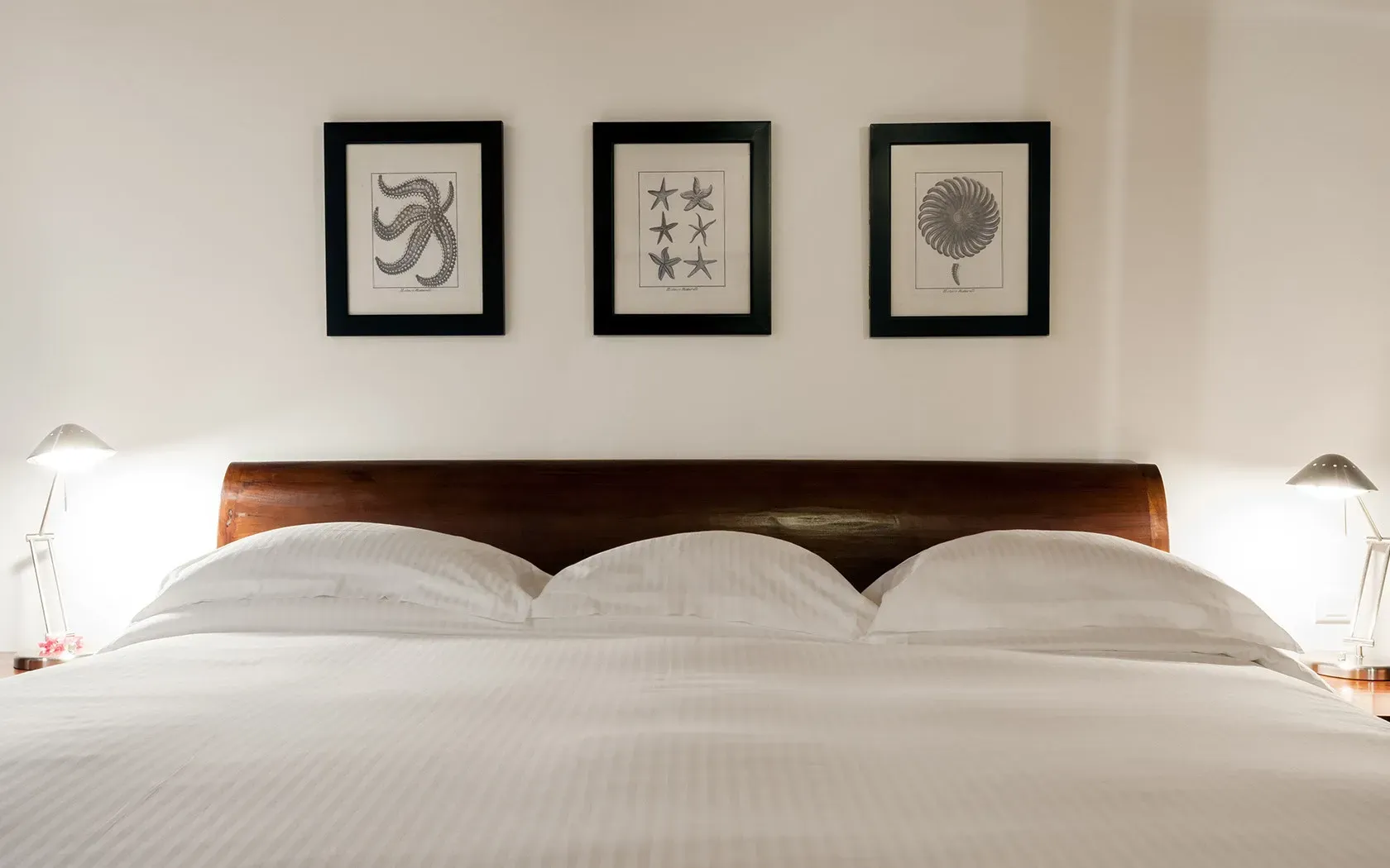 Bedroom with a bed, lamps, and framed art above the headboard.