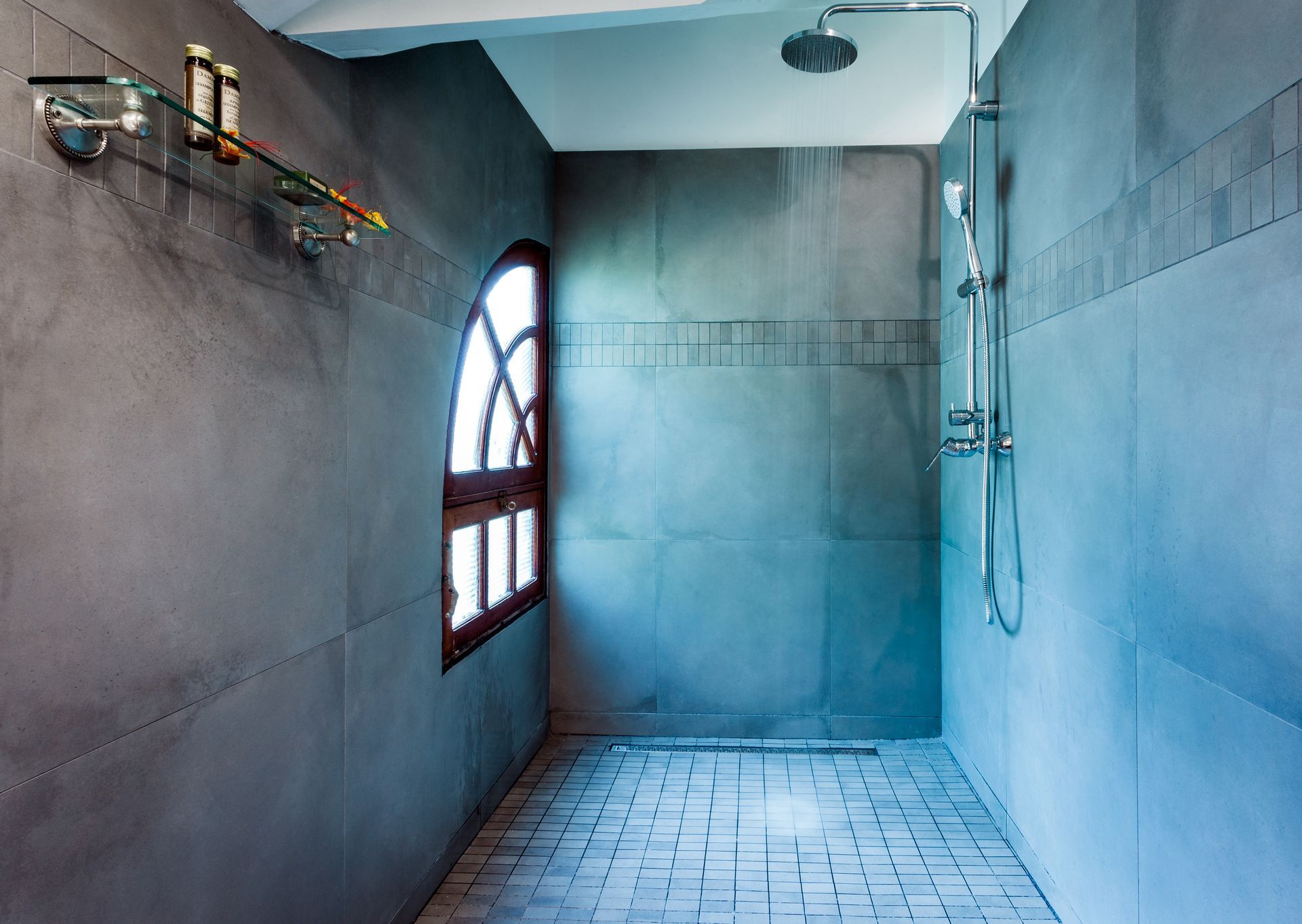 Modern shower room with arched window and gray walls.