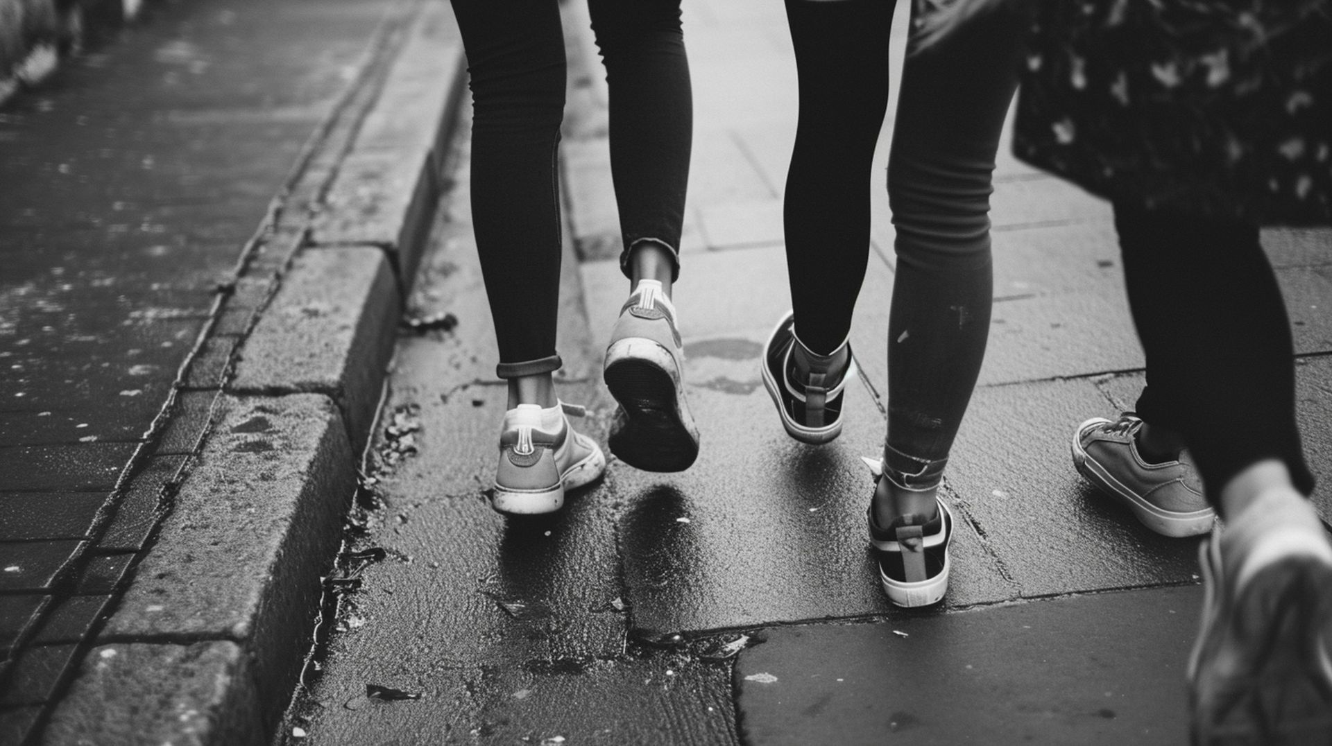 A black and white photo of three people walking down a sidewalk.