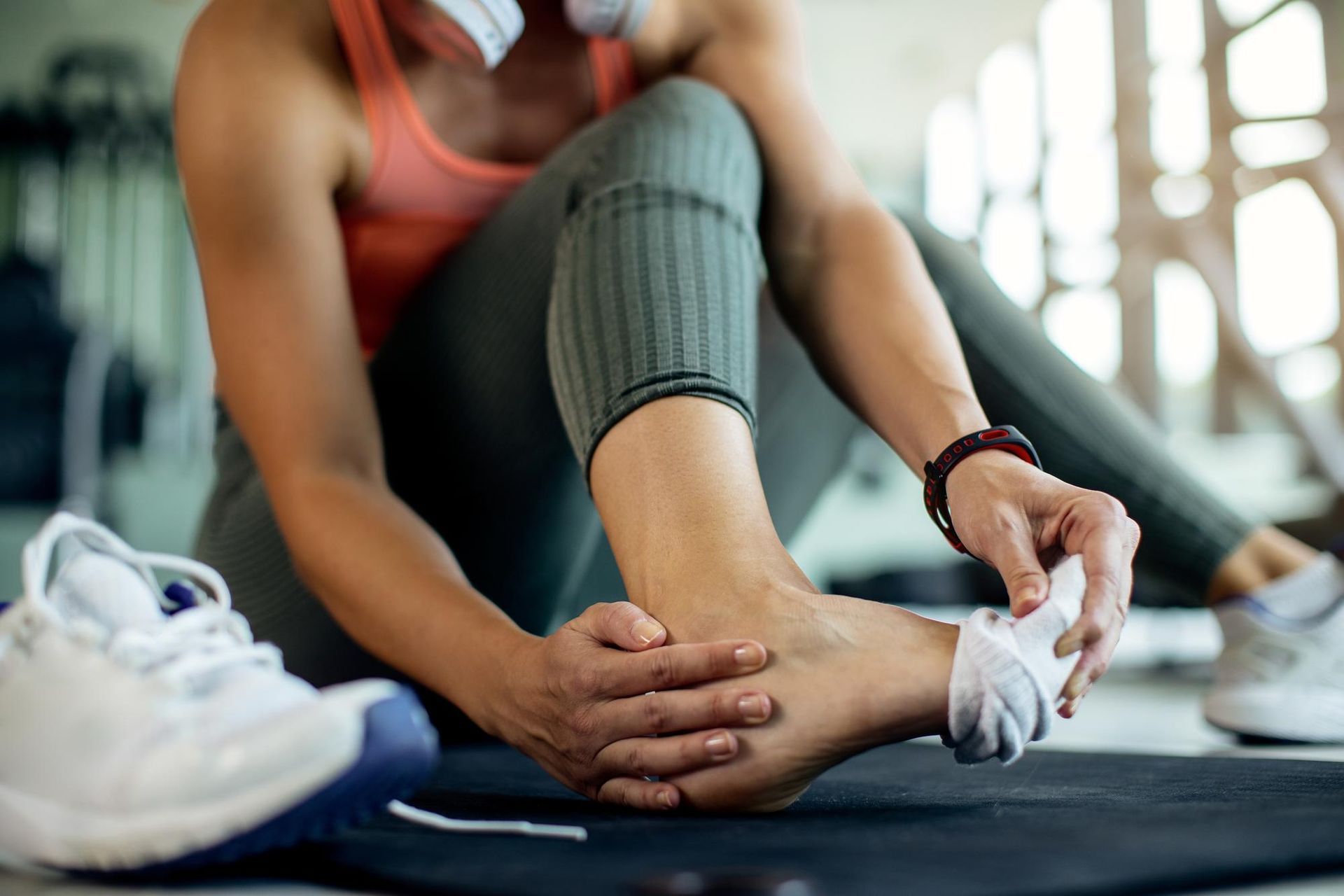 A woman is sitting on the floor putting on a pair of socks.