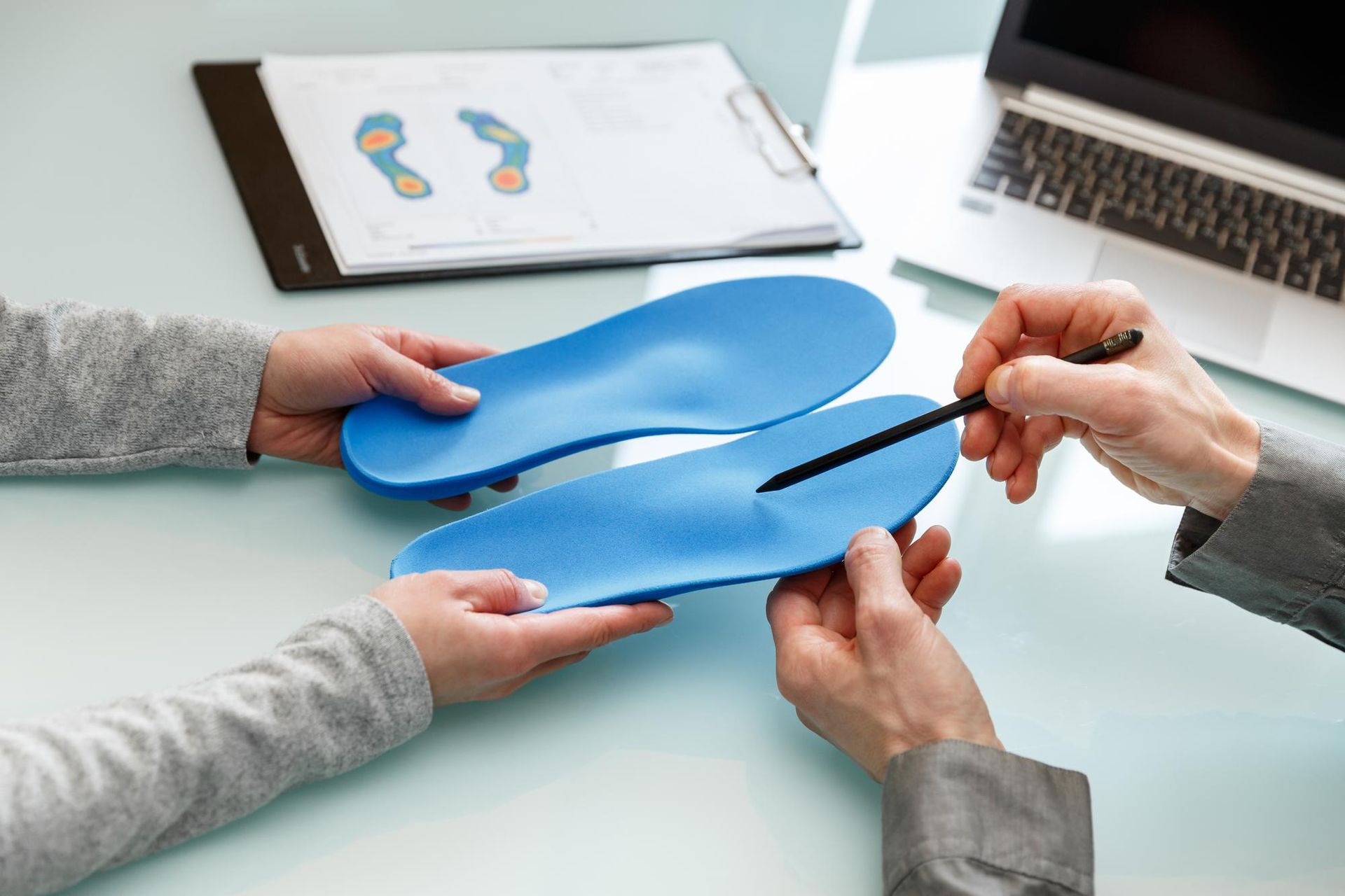 A person is holding a pair of blue insoles in their hands.