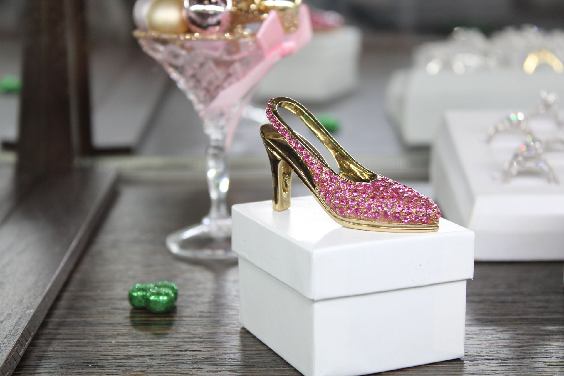 a pink shoe is sitting on a white box next to a martini glass .