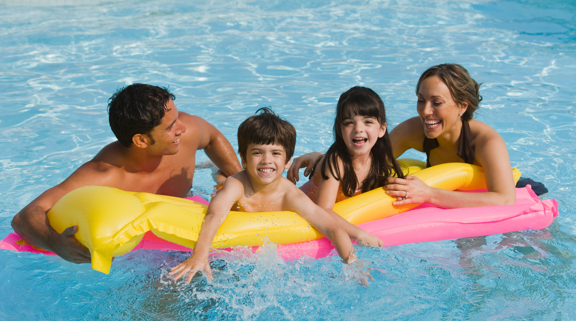 A family is floating on an inflatable raft in a swimming pool.