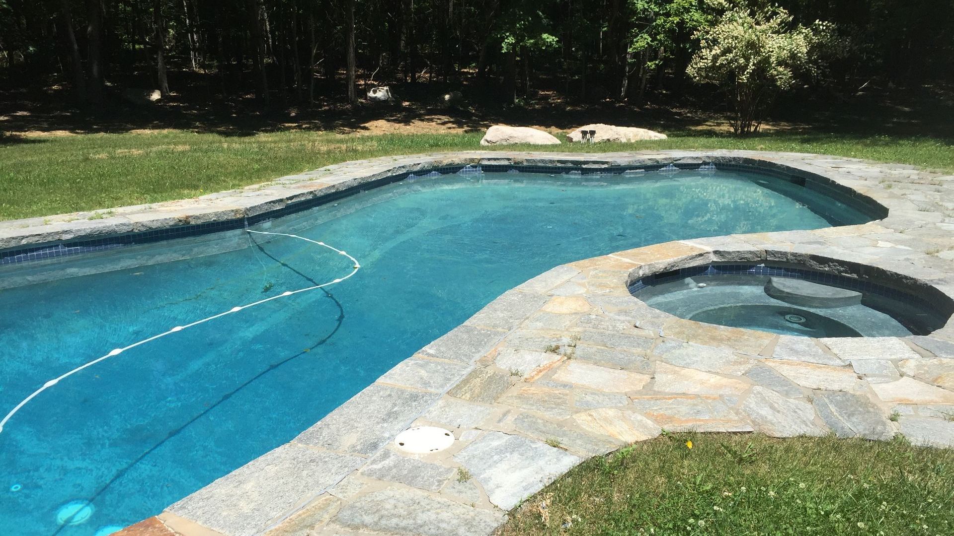 A large swimming pool with a hot tub next to it