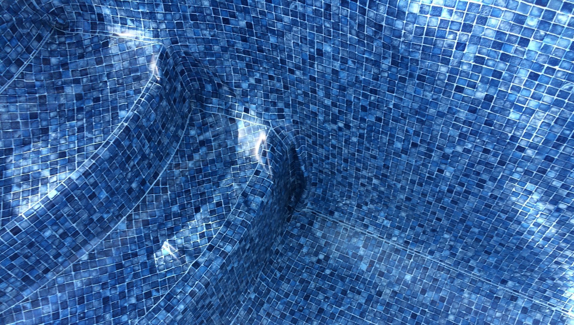 A close up of a blue tiled floor in a swimming pool.