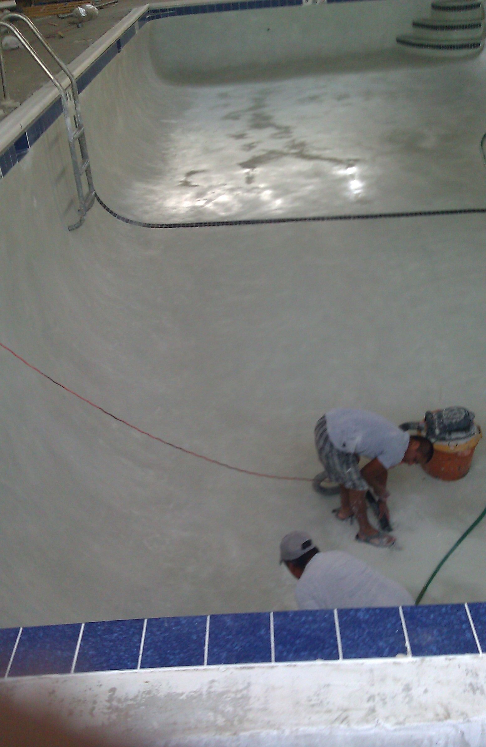 A man is working on the floor of a swimming pool.
