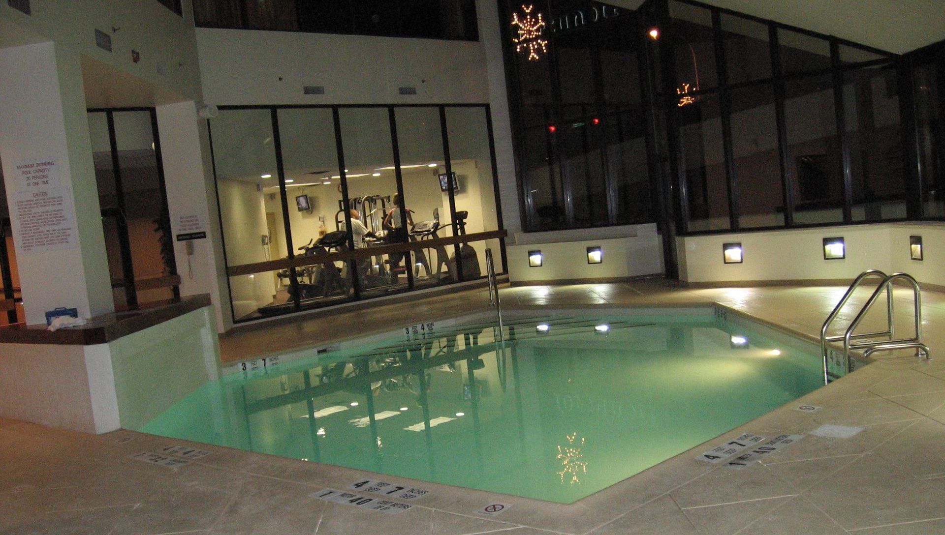 A large indoor swimming pool with a gym in the background