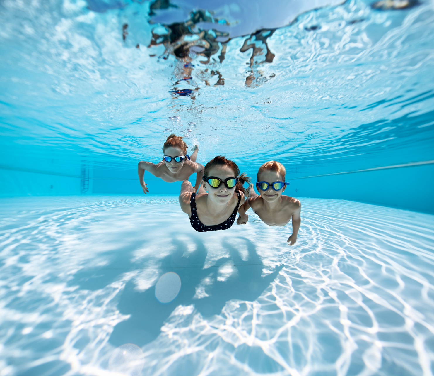 A group of children are swimming underwater in a swimming pool.