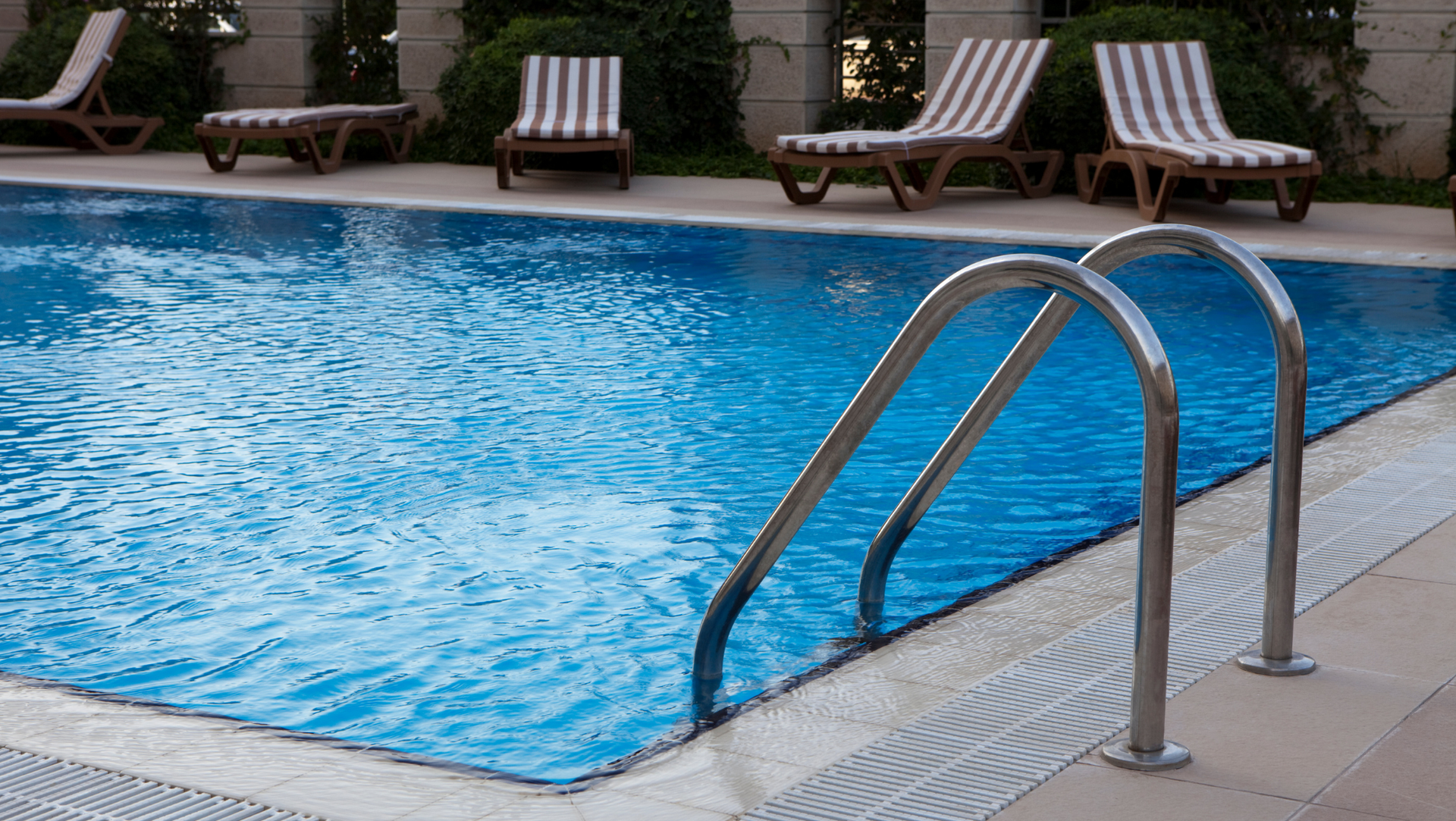 A swimming pool with stairs and chairs around it